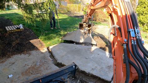 Mini excavator breaking concrete and digging patio 